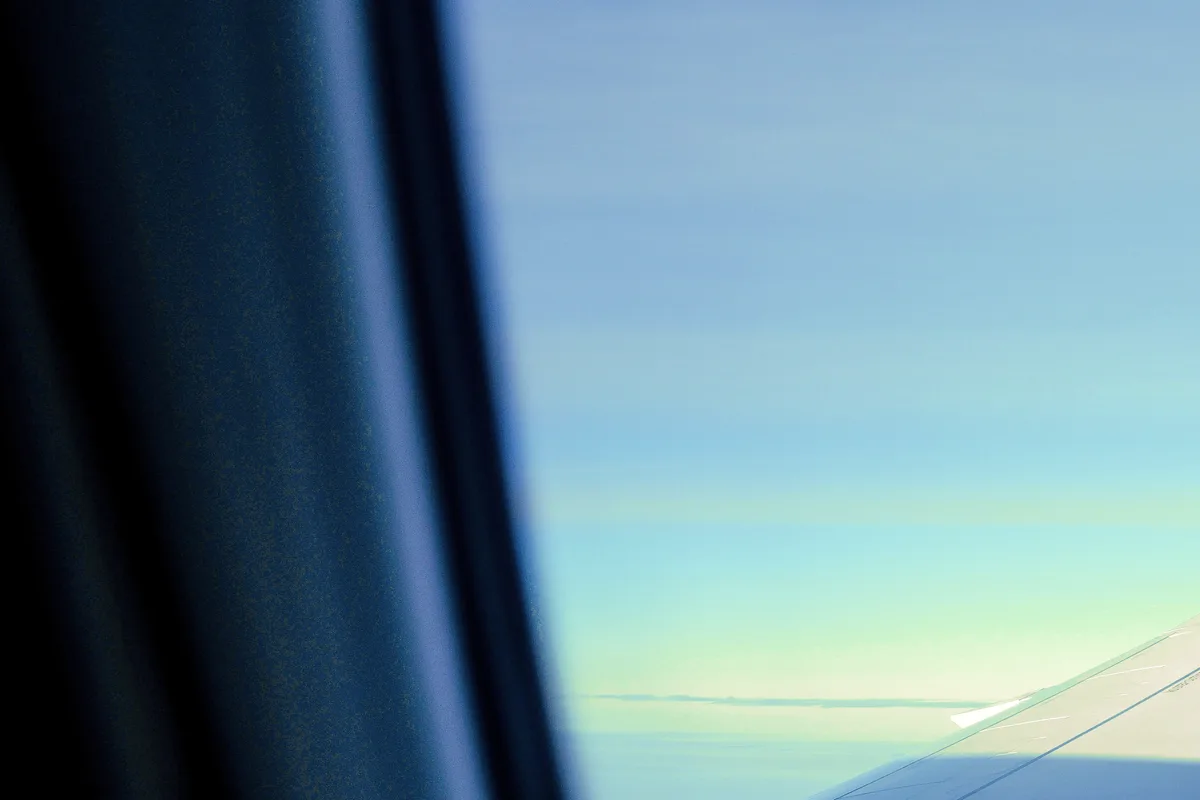 View from an aircraft window over pale blue sky