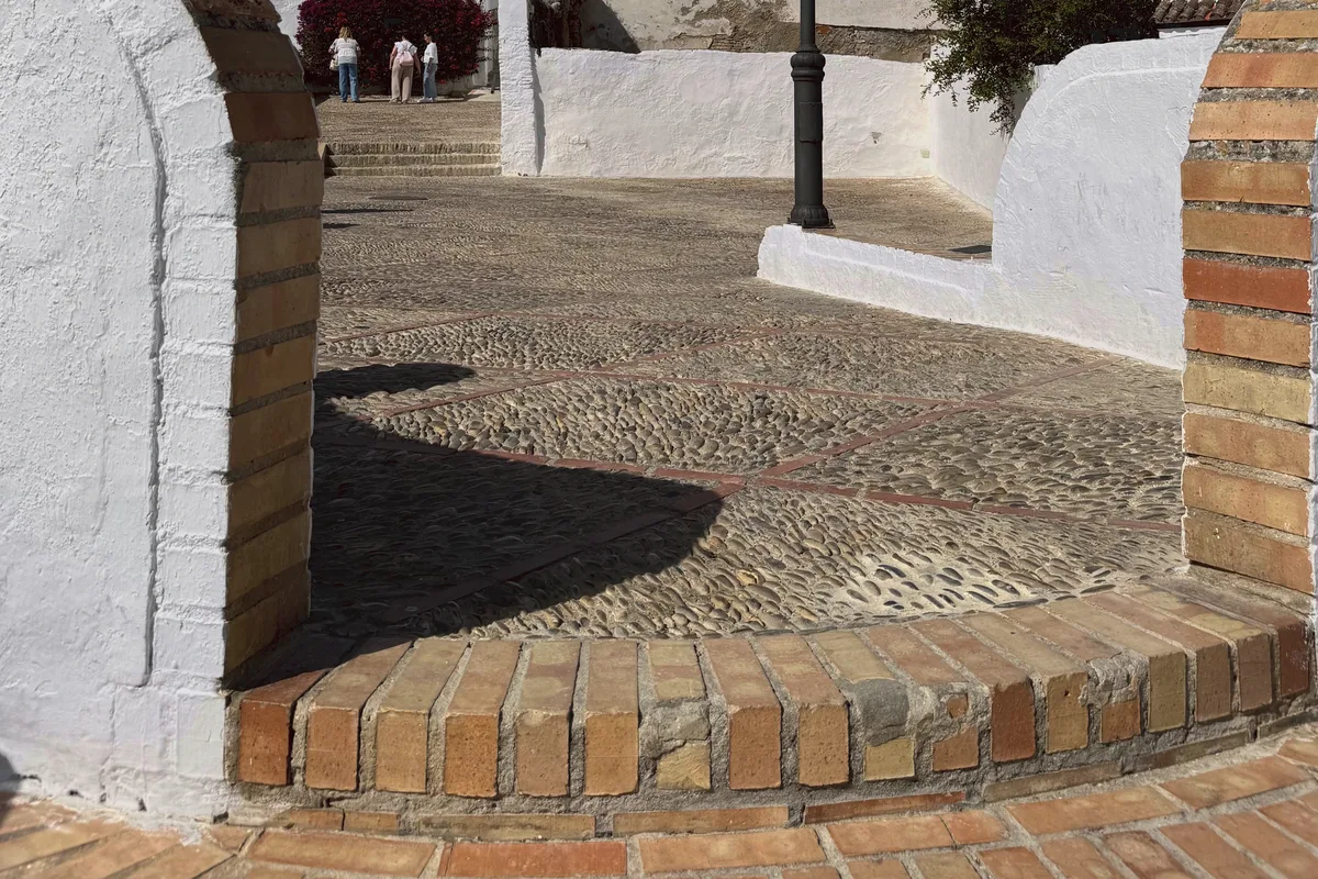 A sunlit cobbled street between white houses in Spain